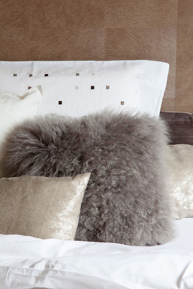 Various cushions made from various materials in front of wall-covered in animal skin