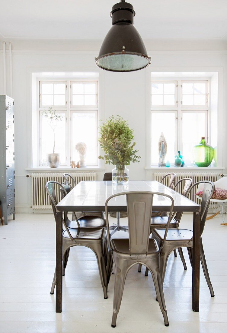 Metal chairs around dining table on white board floor
