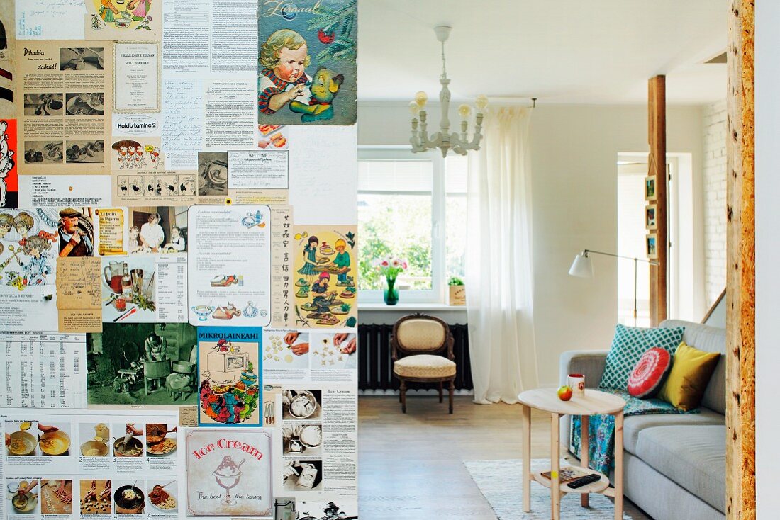 Partition wall papered with magazine clippings and view into living room