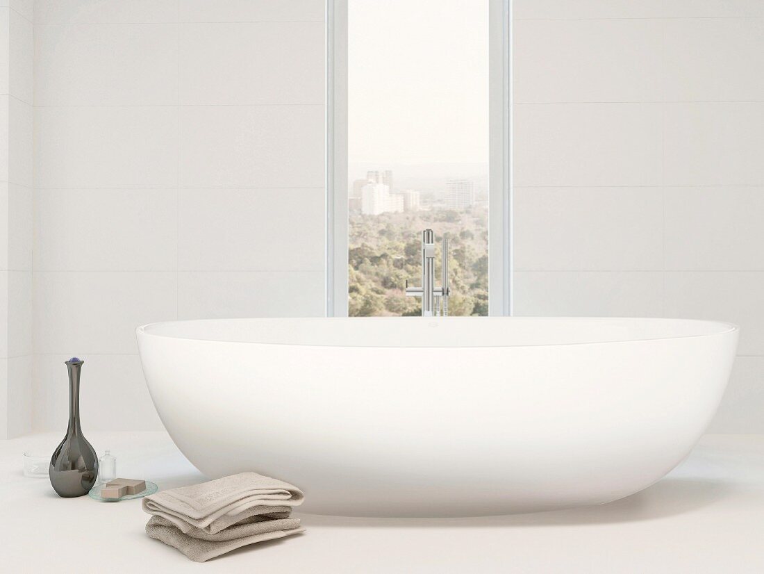 White free-standing bathtub next to vertical window with view