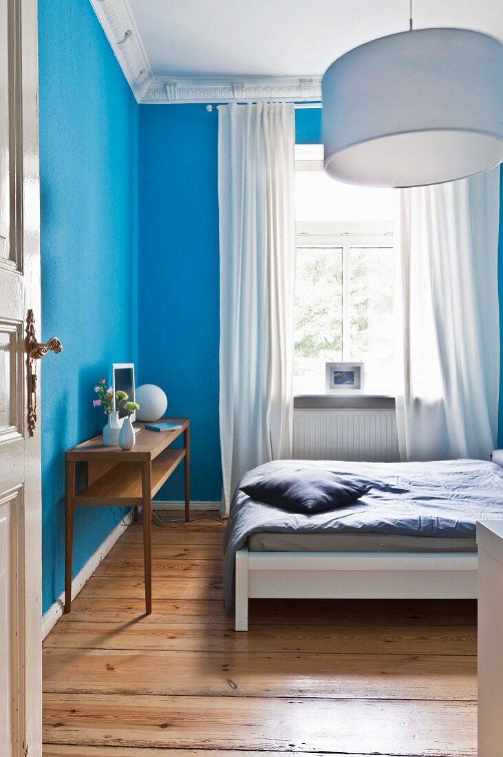 Schlafzimmer mit hellblauen Wänden und Dielenboden in restaurierter Altbauwohnung