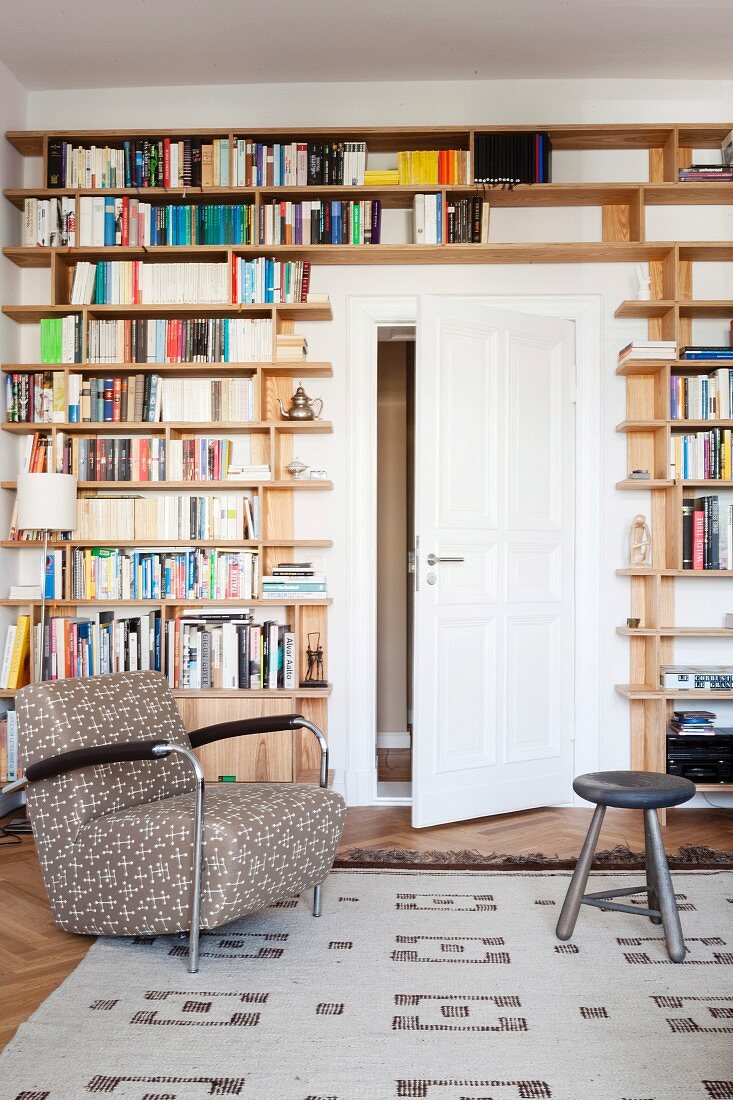 Comfortable armchair in front of bookcase built around white interior door
