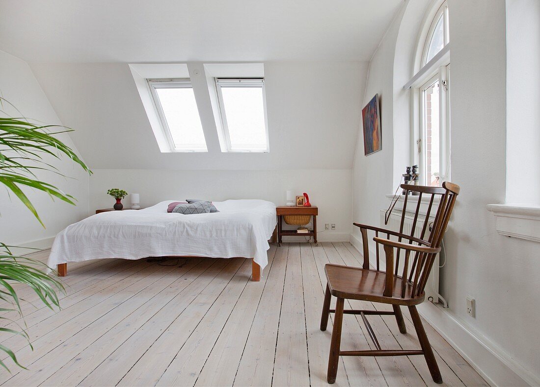 Reduziertes Schlafzimmer mit Armlehnstuhl im Dachgeschoss
