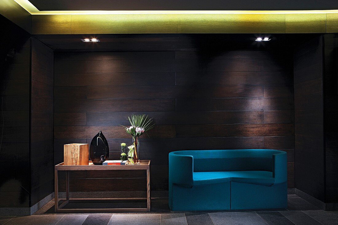 Blue designer sofa and console table against wood-panelled wall