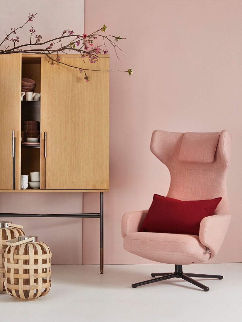 Pink armchair next to cabinet on metal legs in romantic Japanese interior