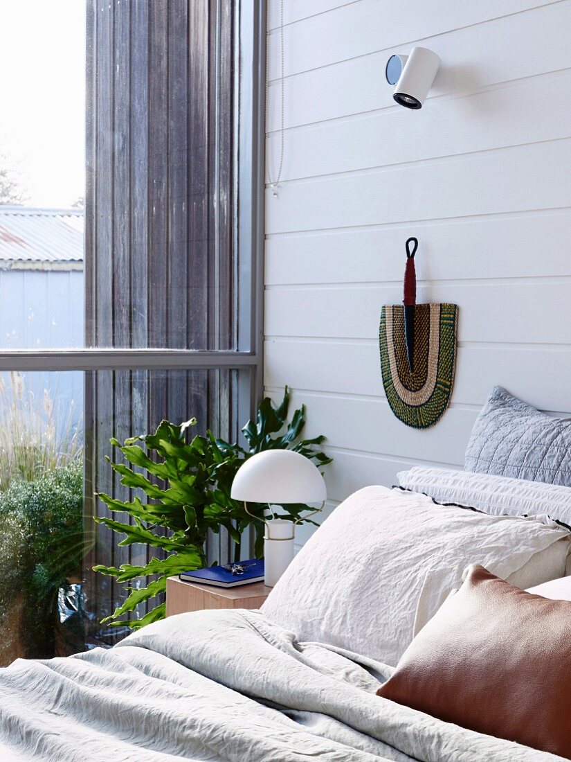 Schlafzimmer mit weiß gestrichener Holzverschalung und Verglasung