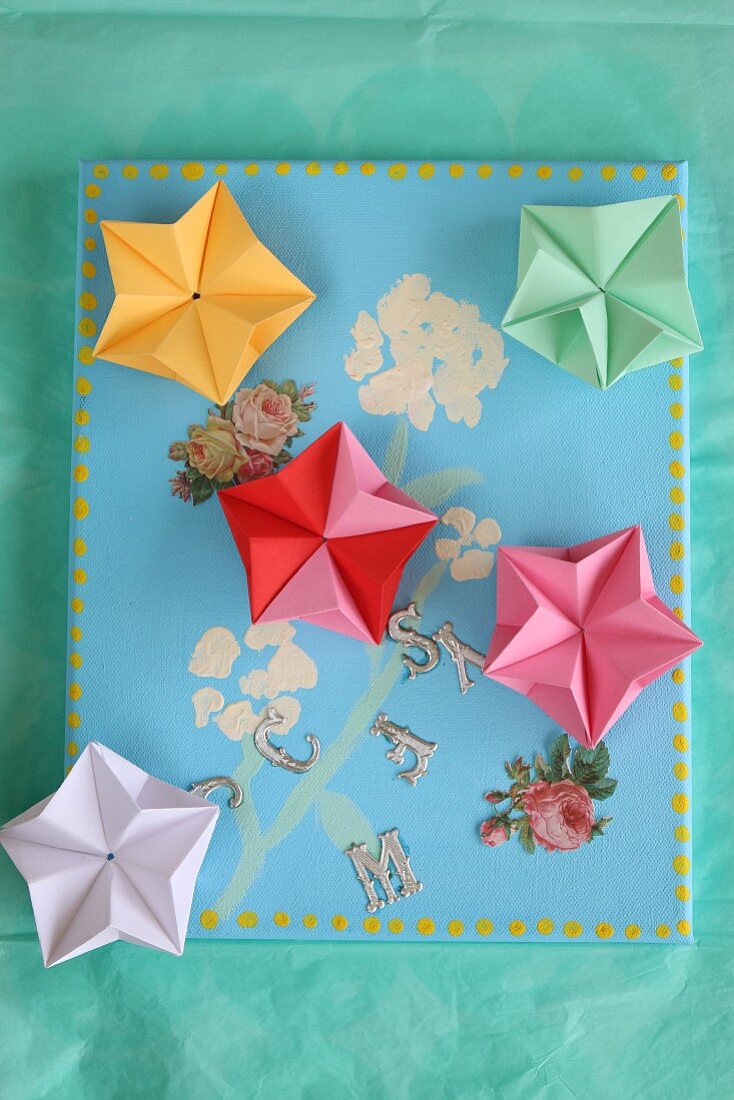 Colourful origami stars on painted canvas with floral decoupage