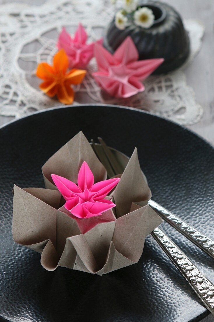 Origamiblumen aus Papier auf einem schwarzen Teller mit Relief