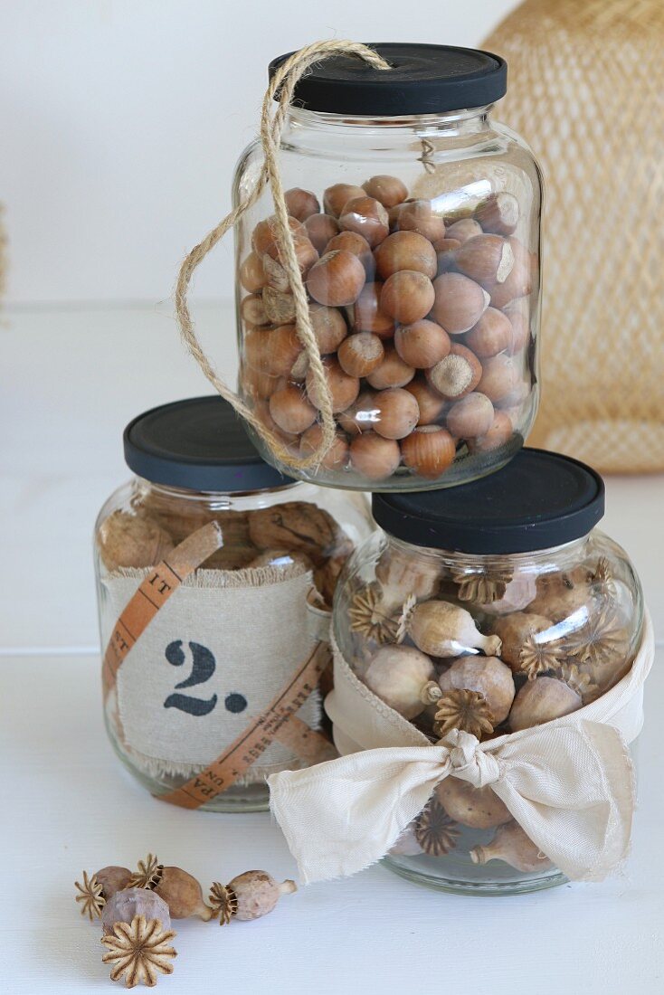 Nuts and poppy seedheads in jars with black screw lids