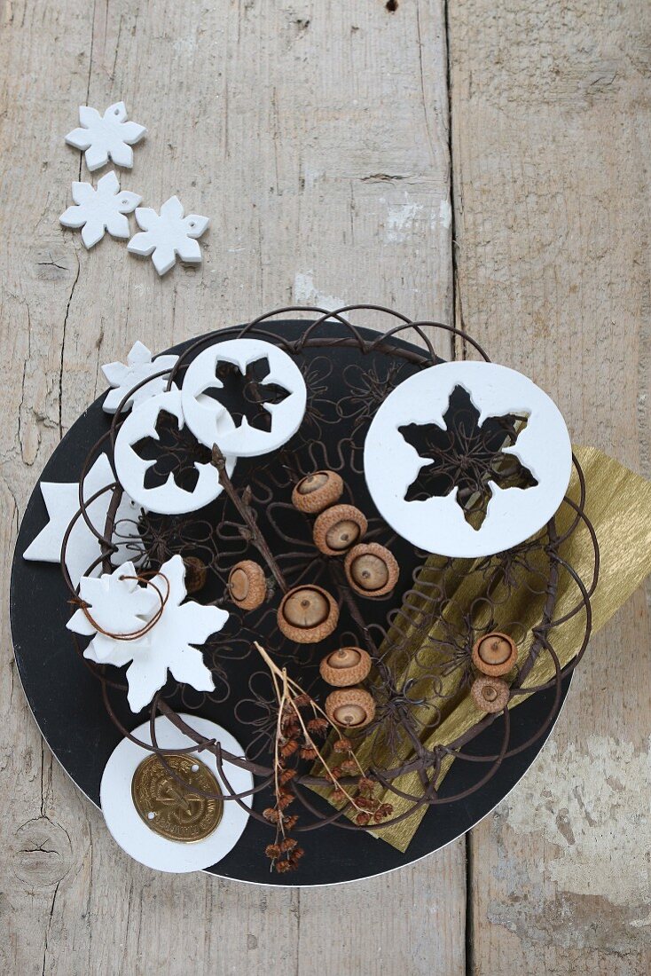 Wintry arrangement of metal basket, snowflakes and acorns
