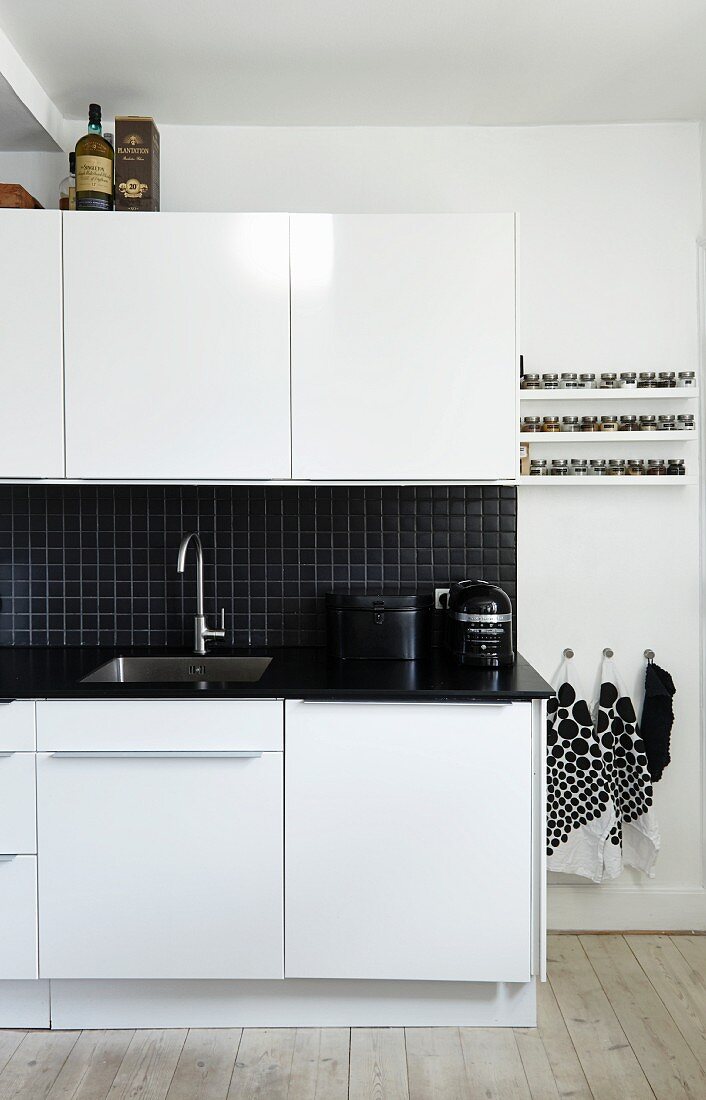 weiße Küche mit schwarzer Arbeitsplatte und Spritzschutz