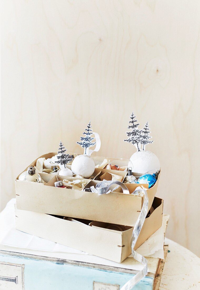 Ausgeschnittene Papierbäumchen auf weiße Weihnachtskugeln geklebt