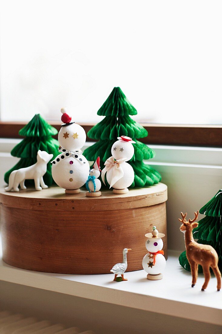 Winterliches Deko-Arrangement mit Schneemannfiguren und Tannenbäumchen
