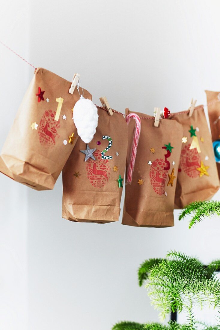 Advent calendar hand-made from decorated paper bags hung from string