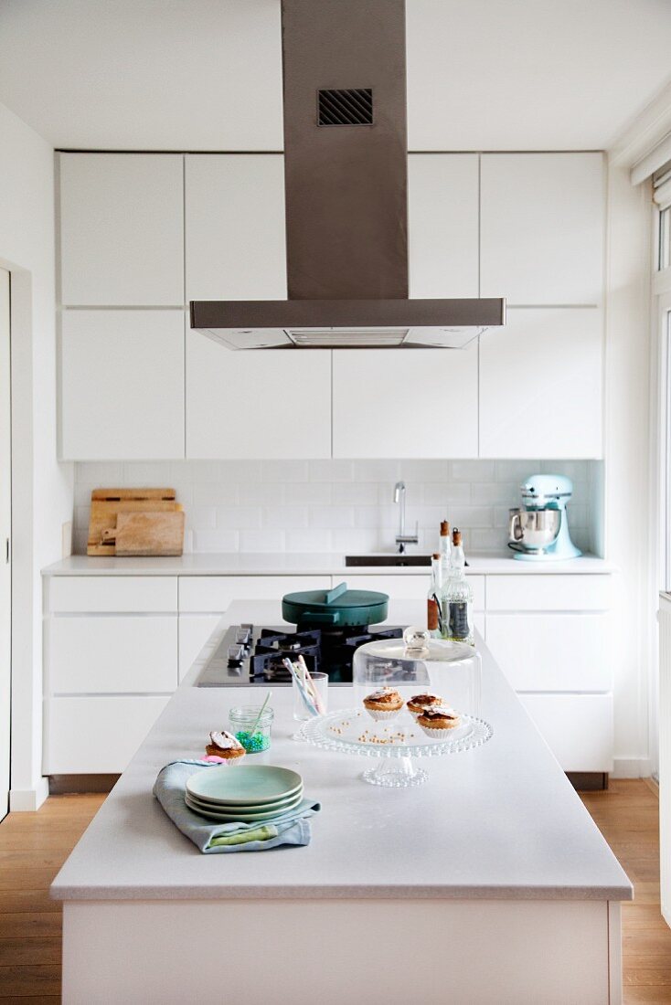 weiße Einbauküche mit Oberschränken, Dunstabzug und Kücheninsel