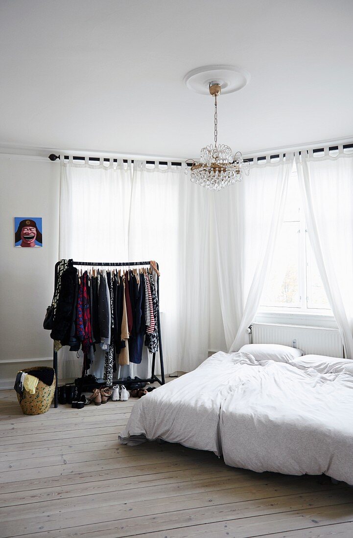 Schlichtes Schlafzimmer mit Kleiderständer und Dielenboden