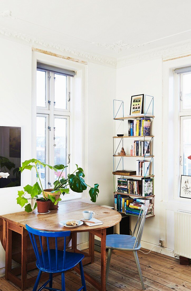 Ausklappbarer Holztisch mit Grünpflanzen und Bücherregal in Zimmerecke