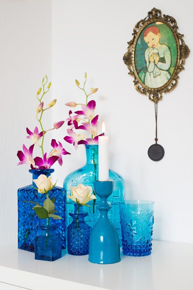Sammlung verschiedener blauer Vasen mit Orchideen und Rose