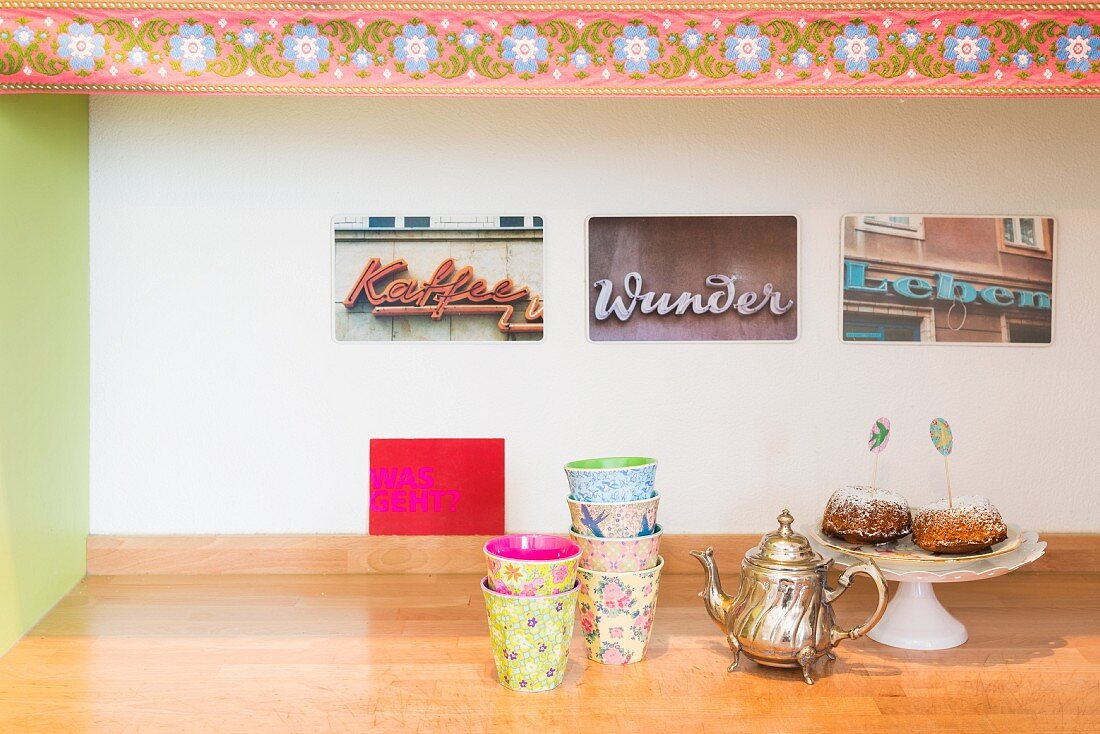 Colourful beakers and vintage jug in front of photos of vintage adverts