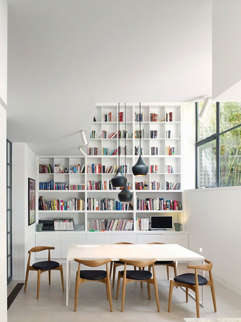 Modernes Esszimmer in hohem Raum mit Bücherregal und Retrostühlen