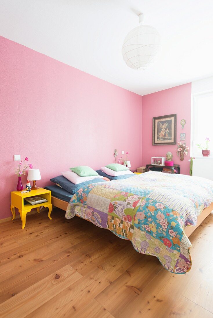 Pink walls and yellow bedside table in colourful bedroom