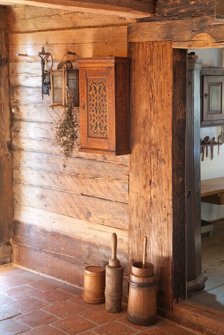 Old butter churns against rustic wooden wall