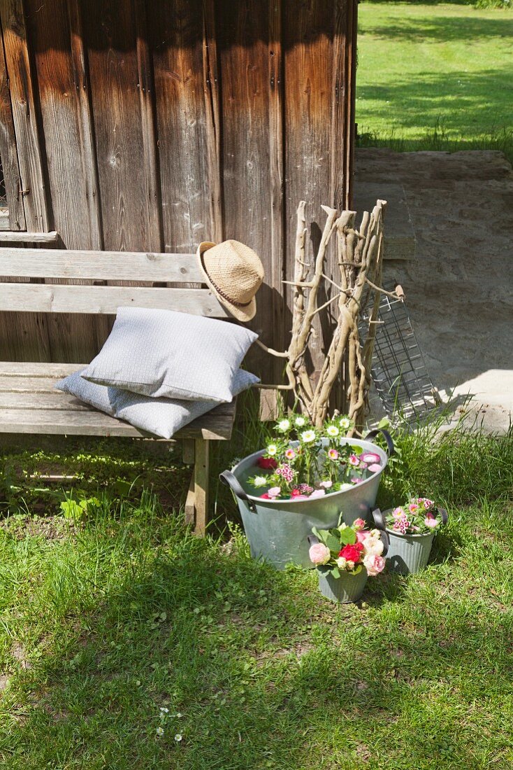 Zinc tub and buckets decorated with flowers outside wooden cabin