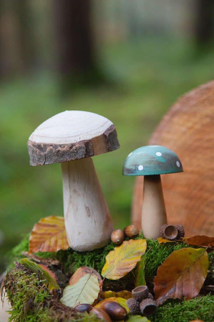 Zwei Pilze aus Holz mit Moos, Laub und Eicheln im Wald