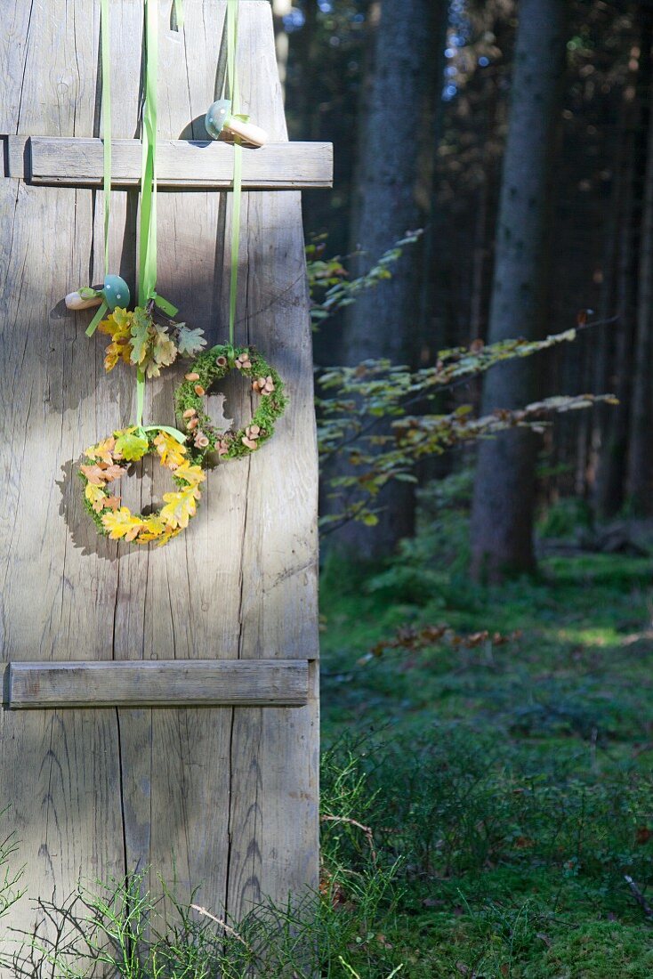 Mit Kränzen und Holzpilzen dekorierter Fensterladen im Wald