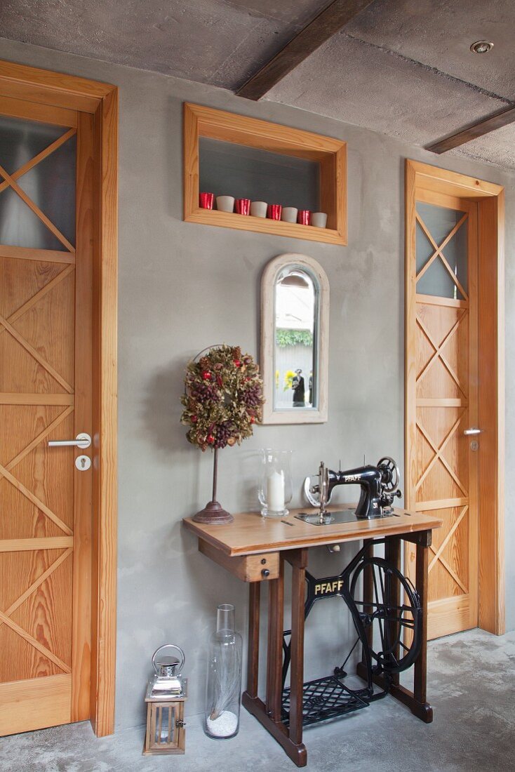 Nähmaschine dekorativ zwischen zwei Landhaus-Zimmertüren an Betonwand