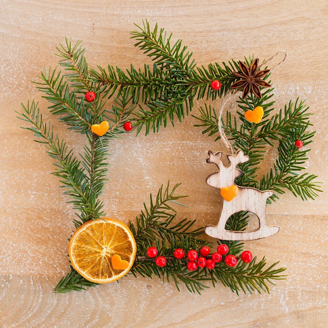 Square frame of fir twigs and decorations on wooden surface