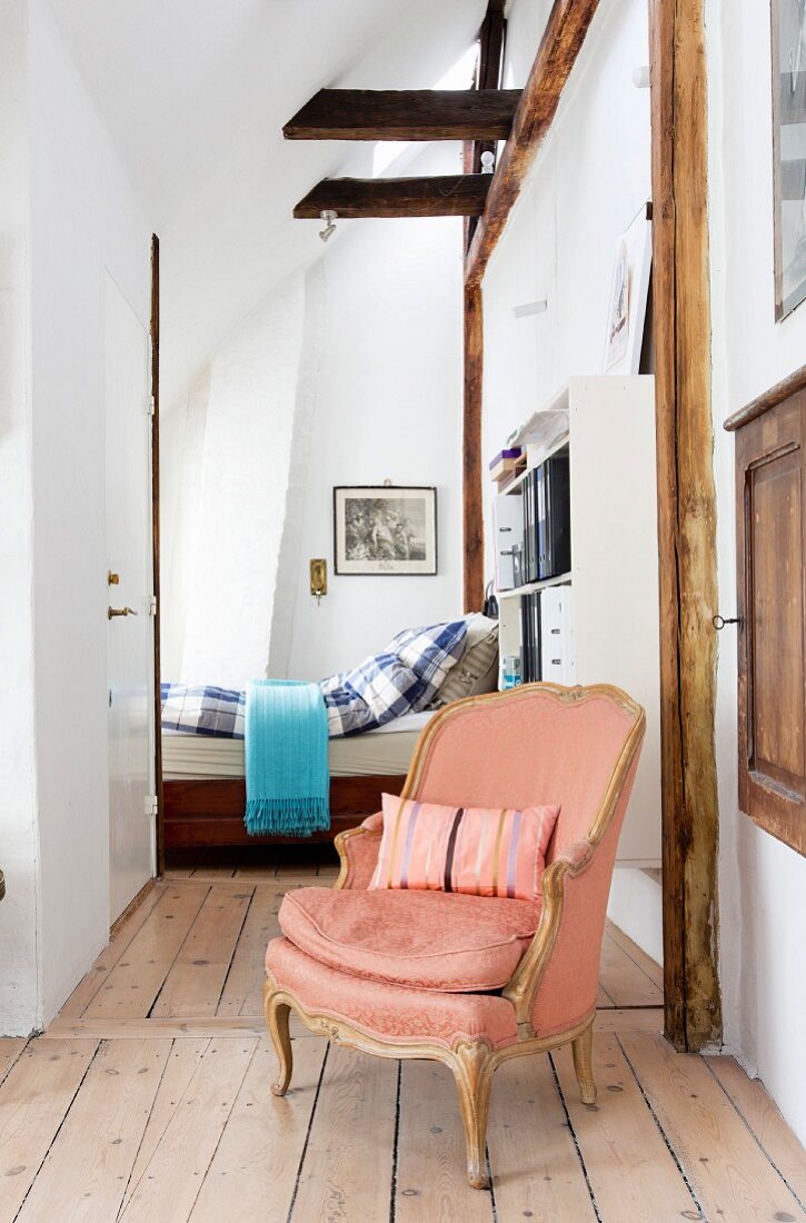 Salmon-pink Baroque armchair in entrance to bedroom with wood-beamed ceiling