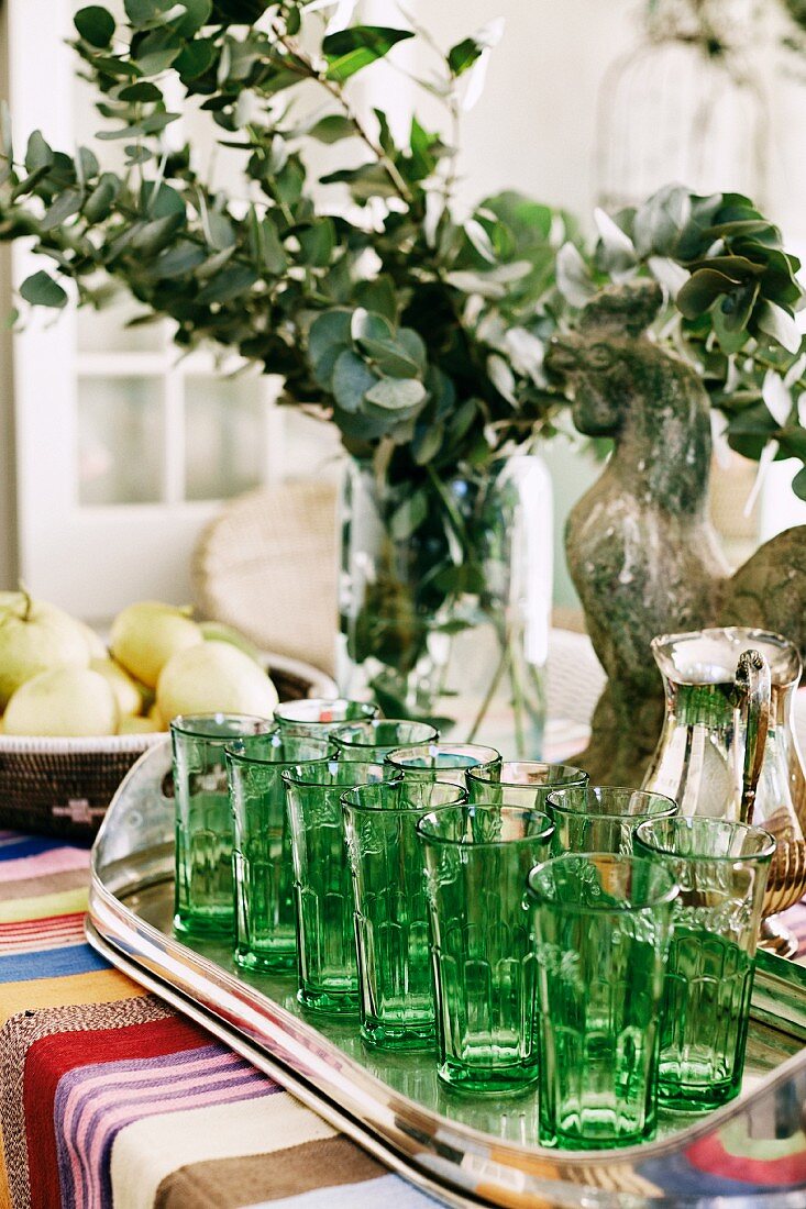 Green glasses on silver tray on colourful tablecloth