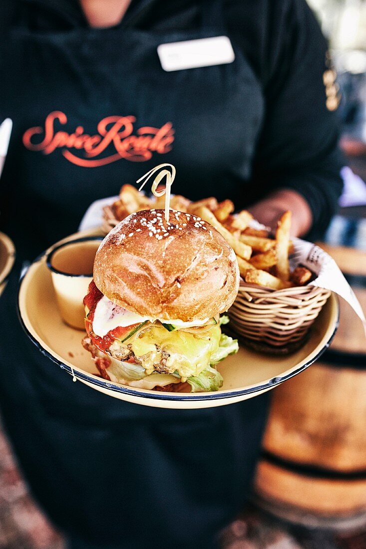 Frau serviert Burger mit Frites, Südafrika