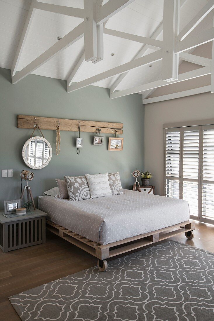 Rustikales Holzbrett mit Haken und aufgehängten Spiegeln im Schlafzimmer mit Fachwerkkonstruktion