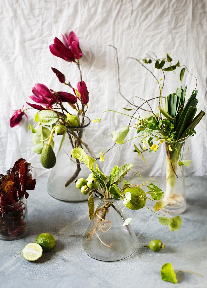 Zweige mit Blüten und Früchten sowie dekoratives Gemüse in Vasen als Naturdeko