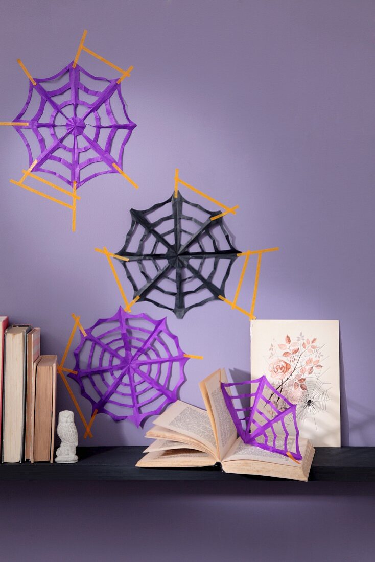 DIY-Spinnennetze aus Papier an lila Wand