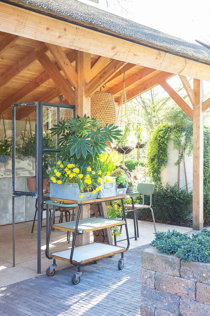 Halboffenes Gartenhaus mit Retro Servierwagen und bepflanzten Zinkgefäßen