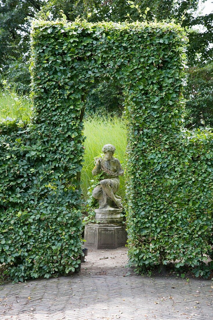 Sculpture framed by opening in clipped hedge