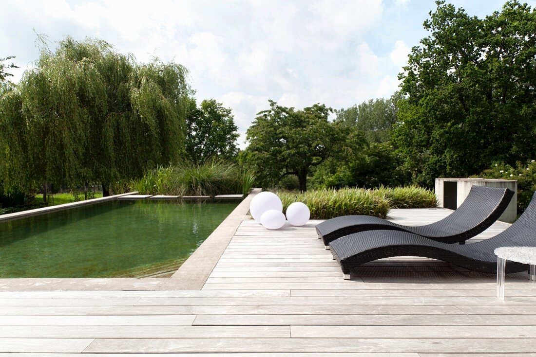 Designer-Sonnenliegen auf Holzterrasse an Pool