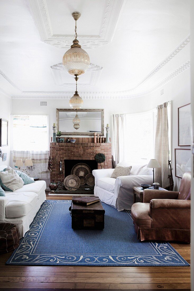 Blauer Teppich im Wohnzimmer mit Stuckdecke und offenem Kamin