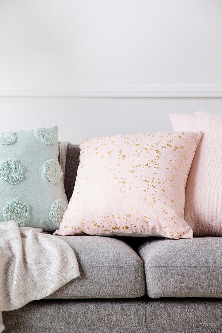Pastel-colored pillows with dots and polka dots on a gray sofa
