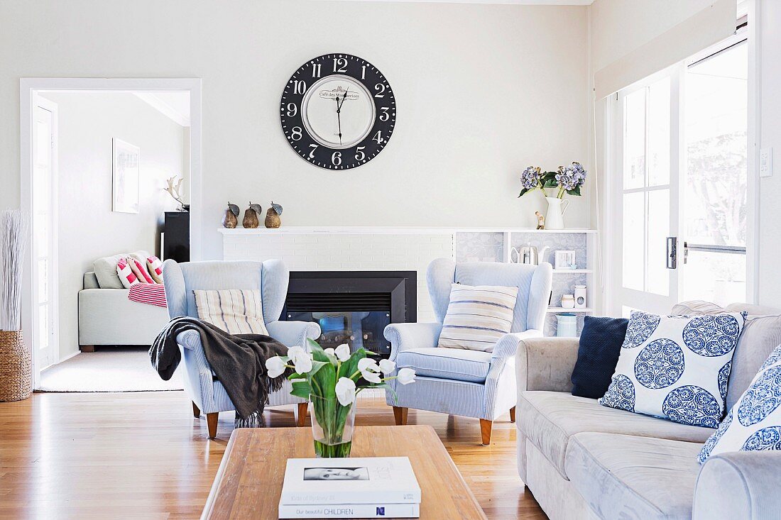 Blue upholstered furniture in the living room with a large wall clock