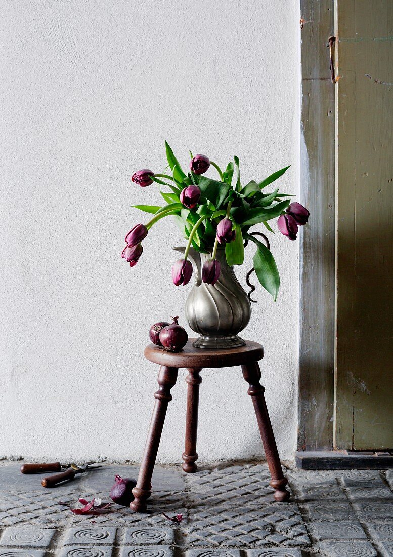 Tulips in pewter coffee pot on stool