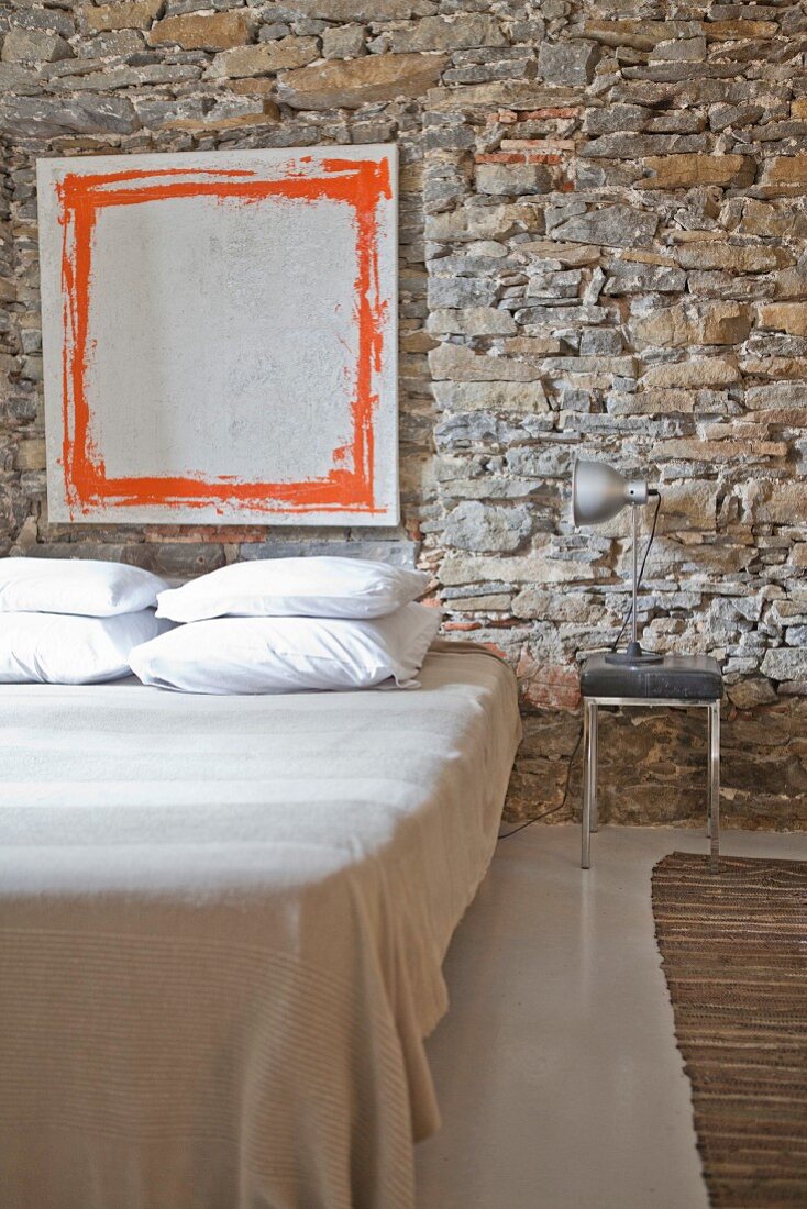 Modern artwork on rustic stone wall in minimalist bedroom