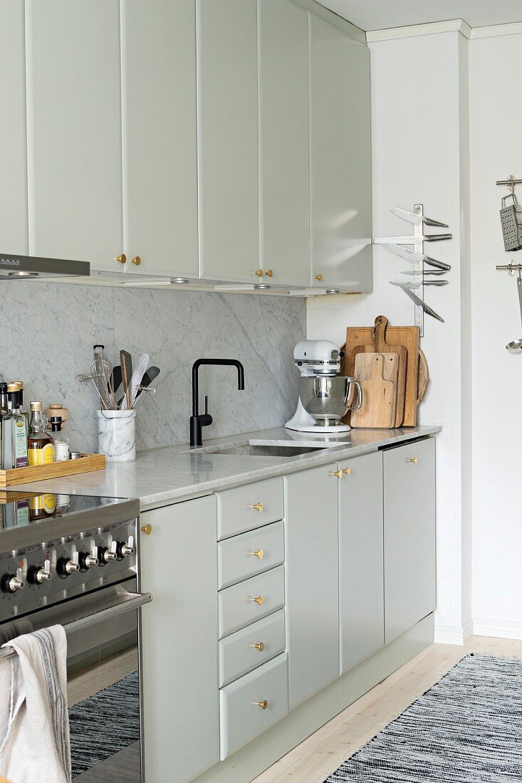 Pale fitted kitchen with wall units, marble worksurface and marble splashback