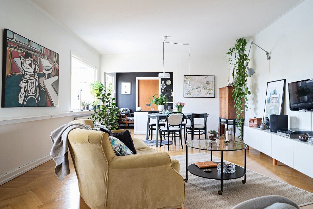 Offener Wohnraum mit gemütlicher Polstercouch, moderner Malerei und Essbereich