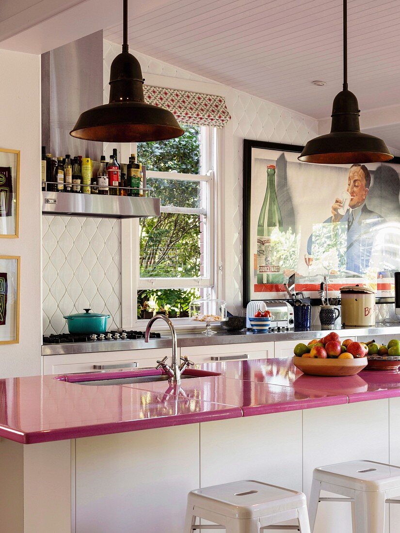 Pinkfarbene Küchenarbeitsplatte auf Küchentheke in offener Küche mit Retro Flair
