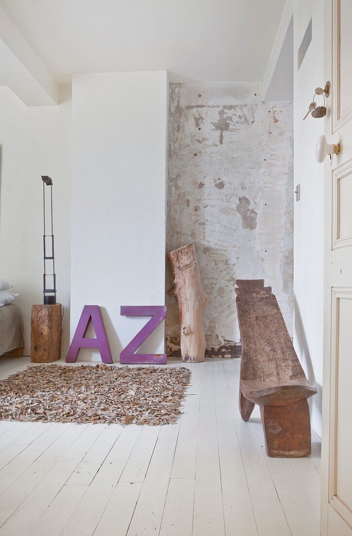 Schlafzimmer mit Leder-Teppich, lila Deko-Buchstaben und Ethno-Holzstuhl