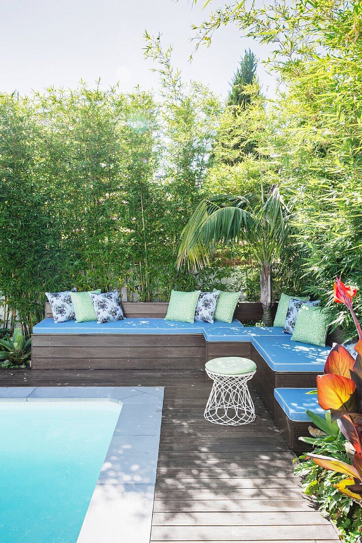Outdoor-Loungeecke aus Holz am Pool mit blauen Polsterauflagen und Zierkissen